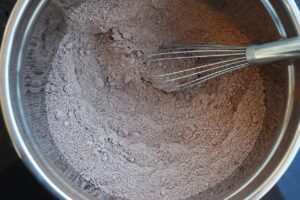 Dry ingredients for chocolate bread whisked together in a mixing bowl with a whisk.