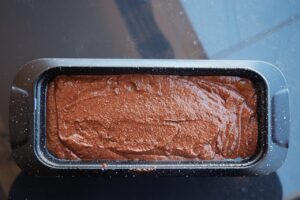 Chocolate bread batter in a loaf pan.