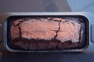 A loaf pan of cooling chocolate bread.