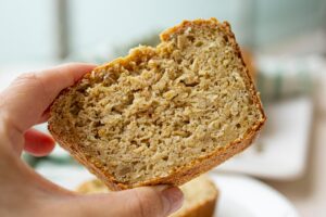 A hand holding a piece of oat bread.