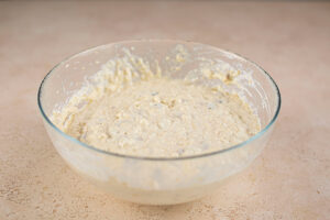 Mixed oat bread batter in a glass mixing bowl.