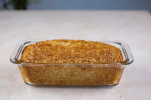 Baked oat bread cooling in a loaf pan.