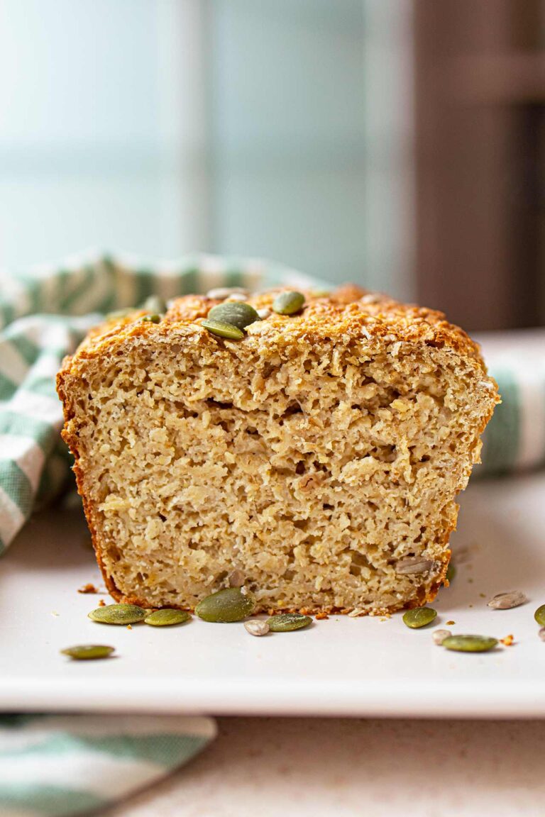 Front view of a cut loaf of oat bread on a white platter.