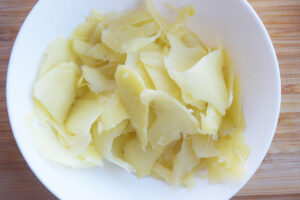 Sliced ginger in a white bowl. Overhead focus.