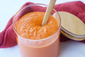Romesco sauce in a jor with a wooden spoon.
