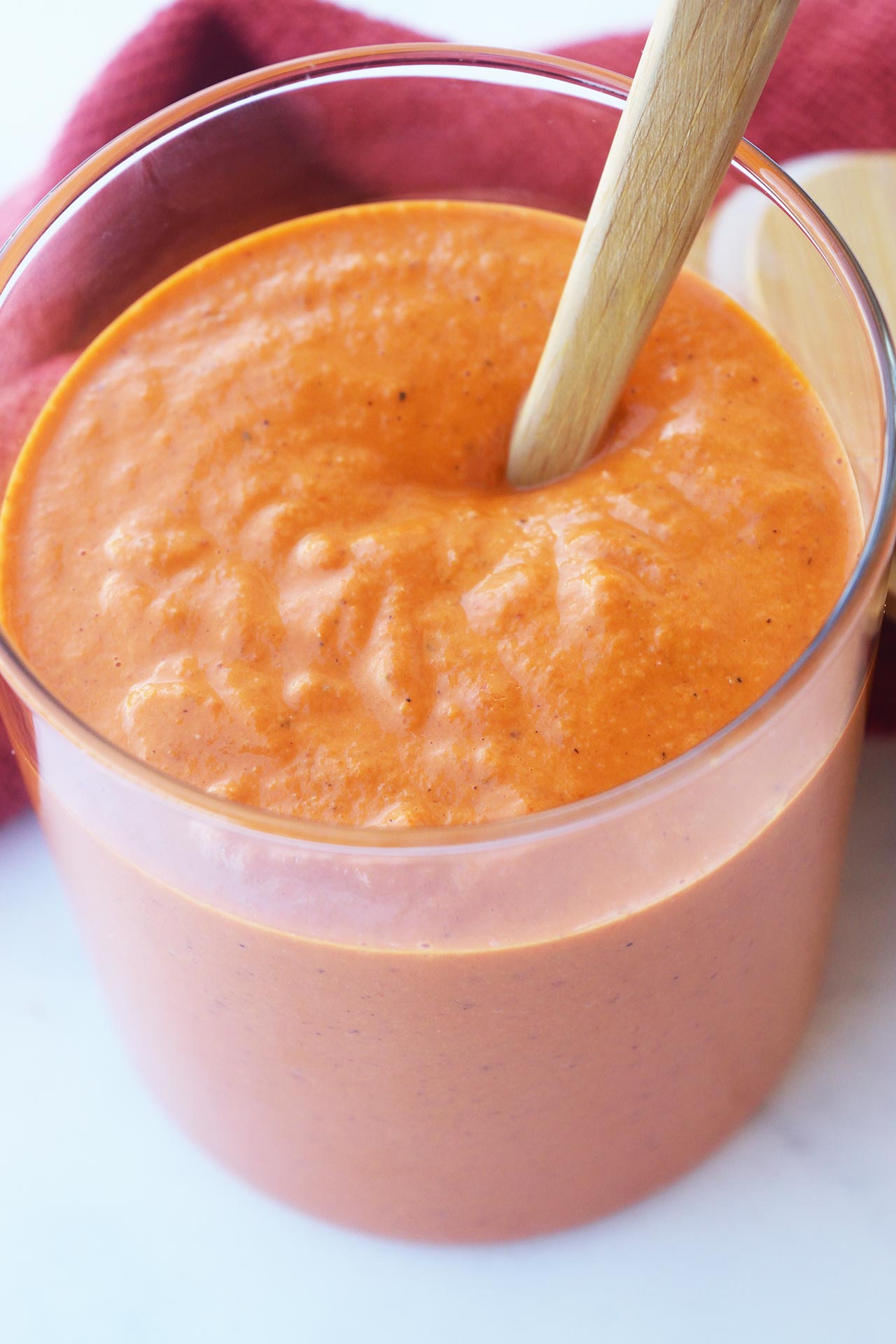 A wooden spoon in an open jar of Romesco Sauce.