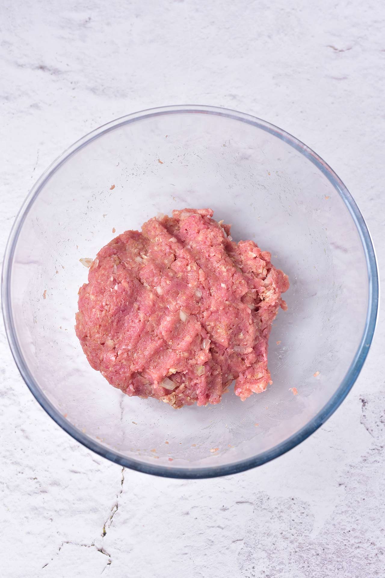 A glass bowl with ground meatball mix.