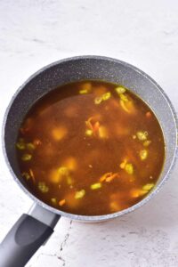 Broth added to a pot of vegetables.