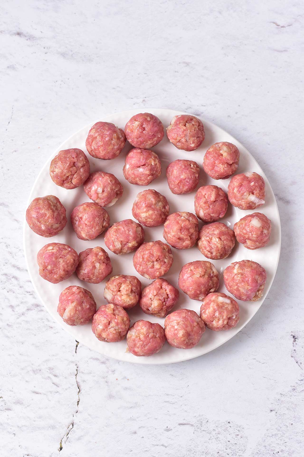 Uncooked meatballs on a plate.
