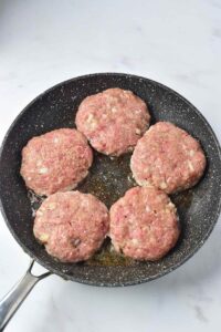 Turkey Salisbury Steak patties in a skillet.