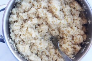 Overhead view of cooked quinoa in a pot. White background.