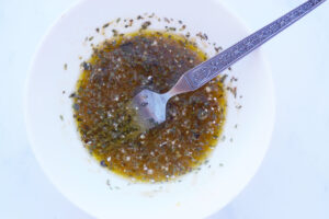 Overhead view. White bowl filled with dressing for a Mediterranean Shrimp Salad. White background.