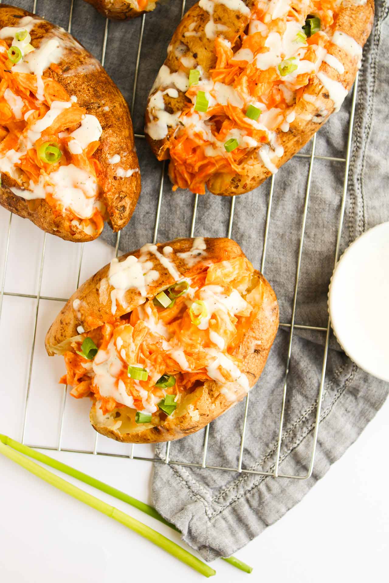 Closeup of Buffalo Chicken Stuffed Baked Potatoes on a cooling rack. Overhead focus.