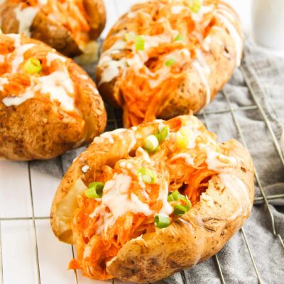 Front view of four Buffalo Chicken Stuffed Baked Potatoes on a wire, metal cooling rack.