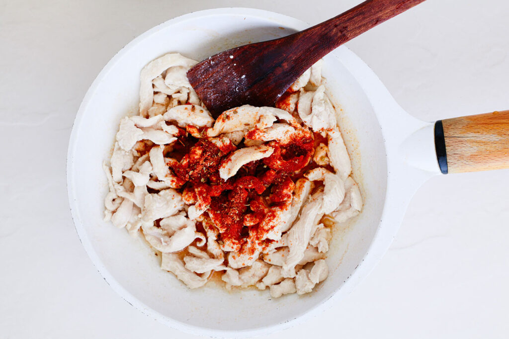 Chicken and seasoning for Chicken Fajita Nachos in a skillet.