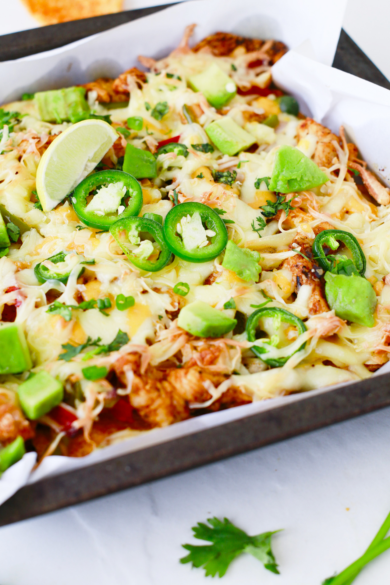 Side view of a sheet pan full of Chicken Fajita Nachos.