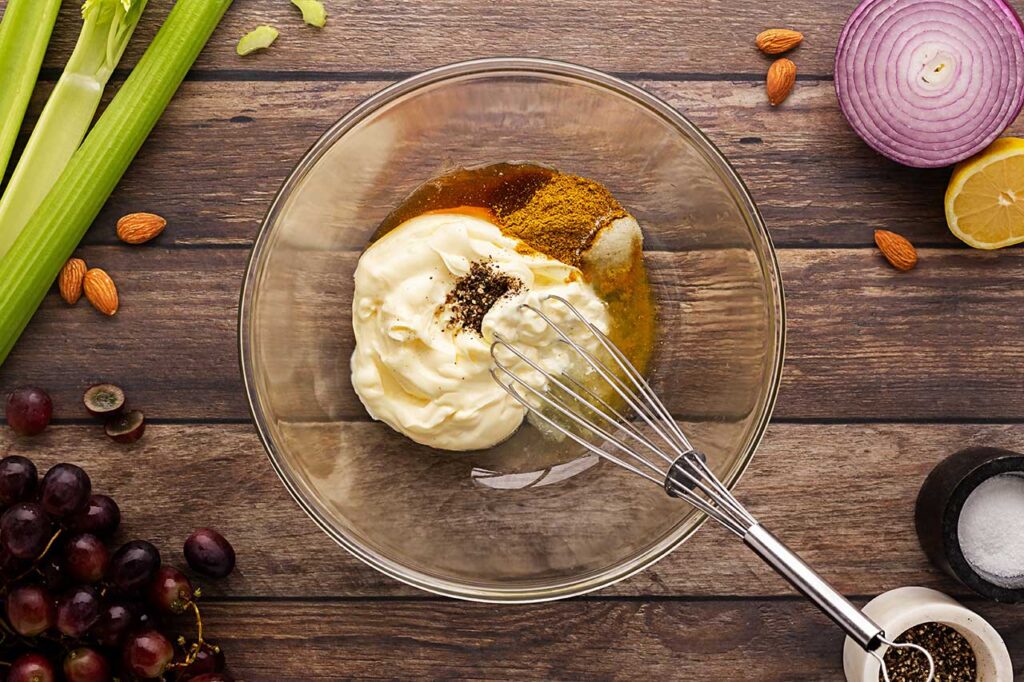 Dressing ingredients in a mixing bowl with a whisk. Overhead focus.