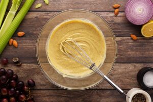 Mixed dressing for curried chicken salad in a mixing bowl with a whisk. Overhead focus.