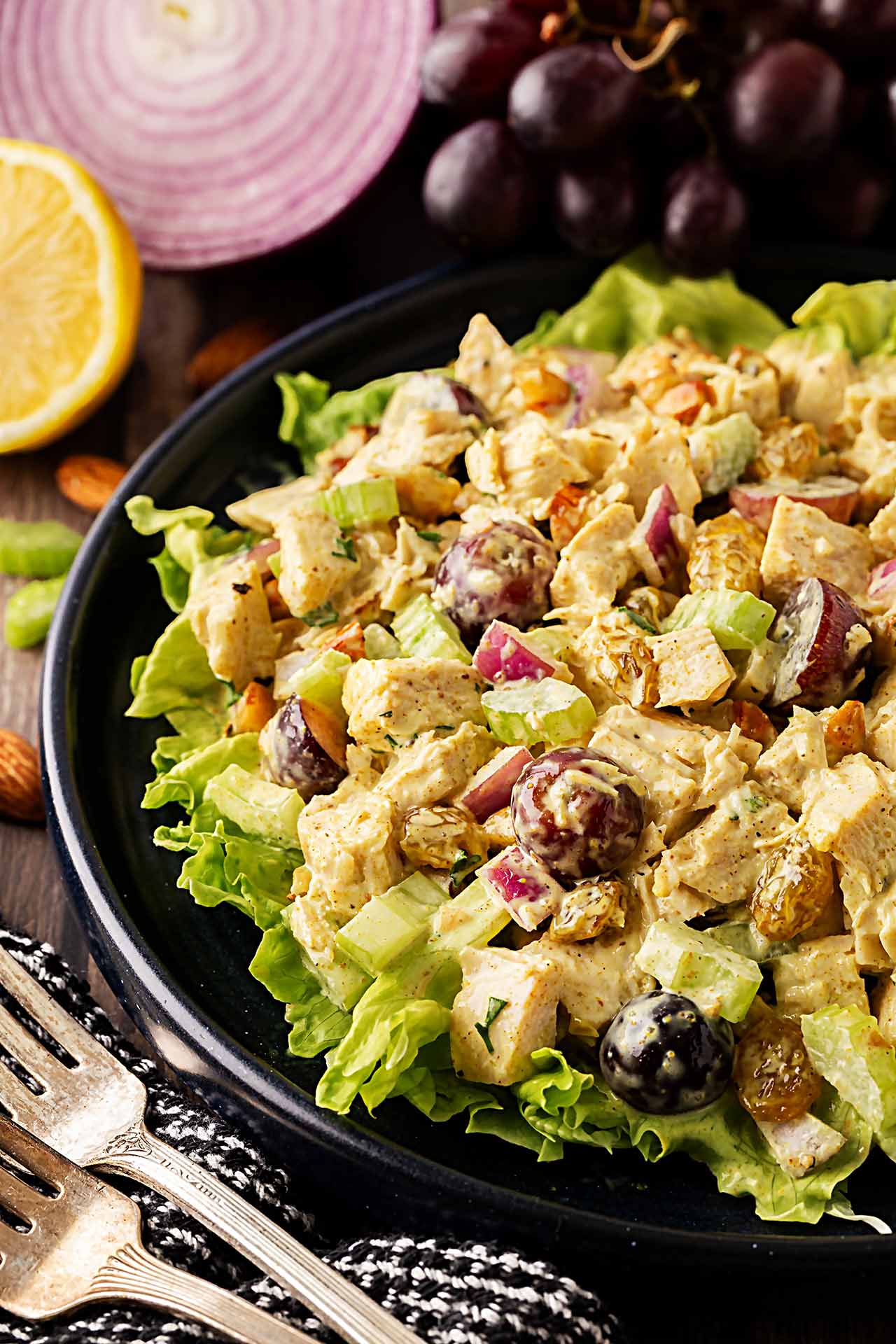 Front, partial view of curried chicken salad on a black plate with salad greens.
