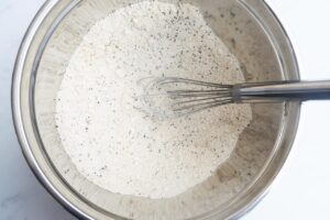 Blended dry ingredients in a metal mixing bowl with a whisk resting in the bowl.