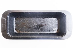 An oiled loaf pan. White background.