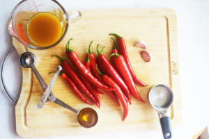 Homemade Sriracha Sauce recipe ingredients gathered on a wood cutting board.