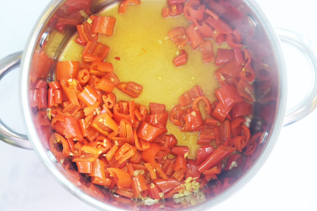 Homemade Sriracha Sauce recipe ingredients cooked in a pot. Overhead focus.