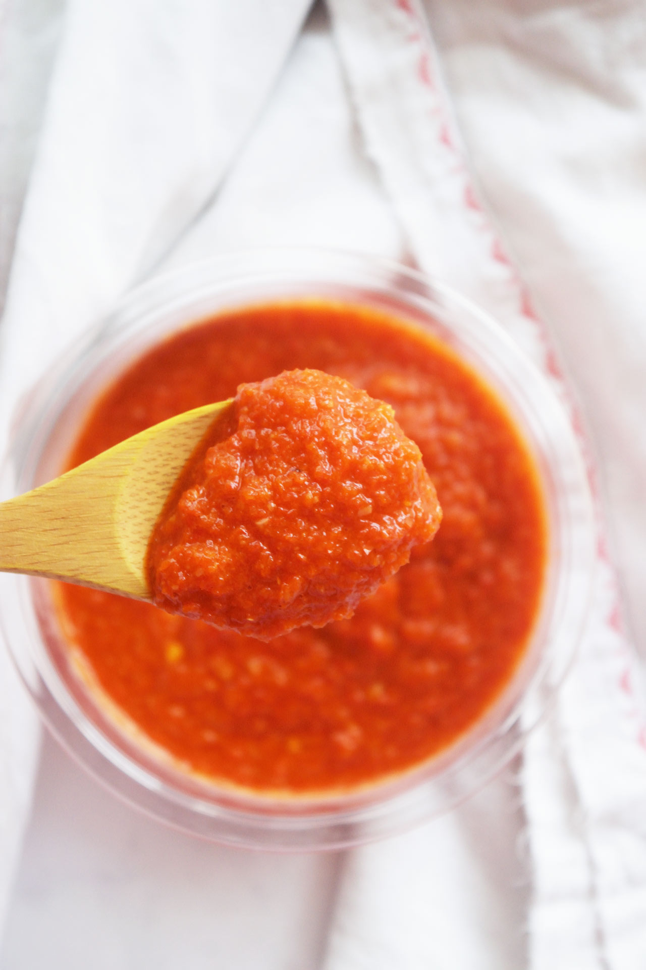 A wood spoon lifts up a scoop of Homemade Sriracha Sauce. Overhead focus.