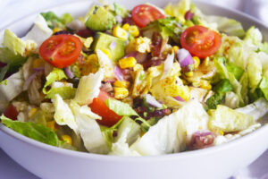 Front, horizontal view of a white bowl holding a Loaded Bacon Salad.