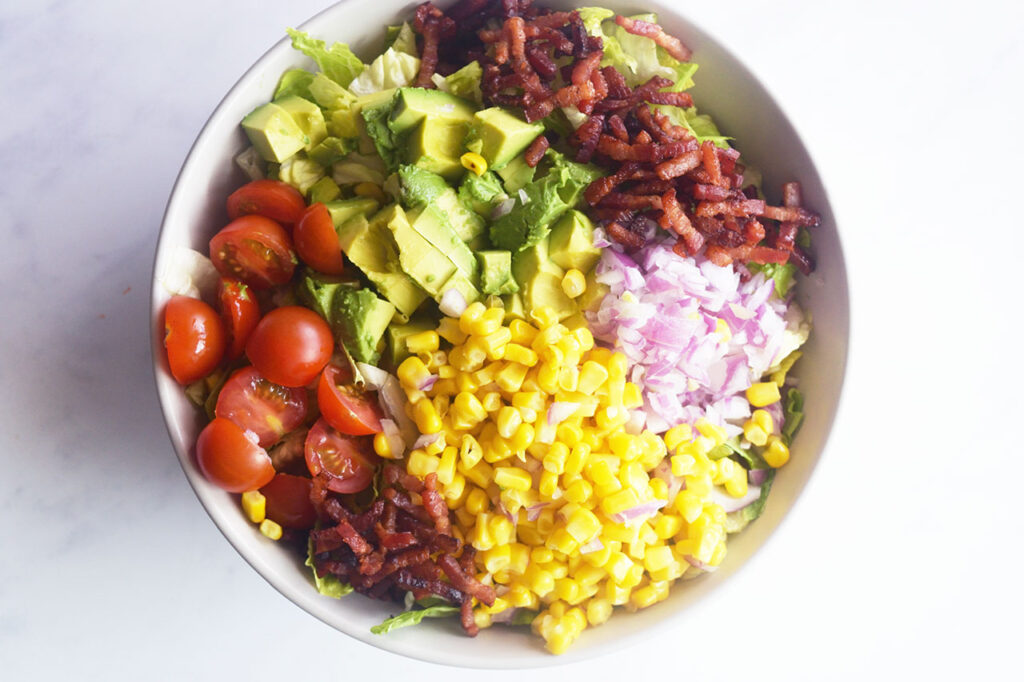 Overhead focus. An assembled Loaded Bacon Salad in a white bowl.