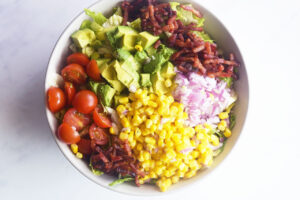 Overhead focus. An assembled Loaded Bacon Salad in a white bowl.