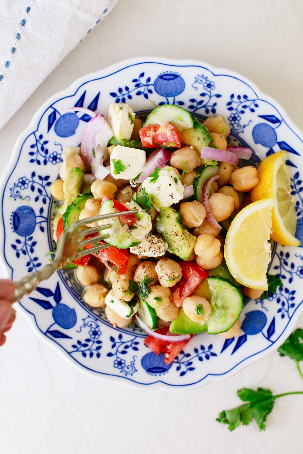 A fork picks up a bite of this Mediterranean Chickpea Salad. Overhead focus.