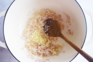 Minced garlic added to onions and ginger in a Dutch oven.