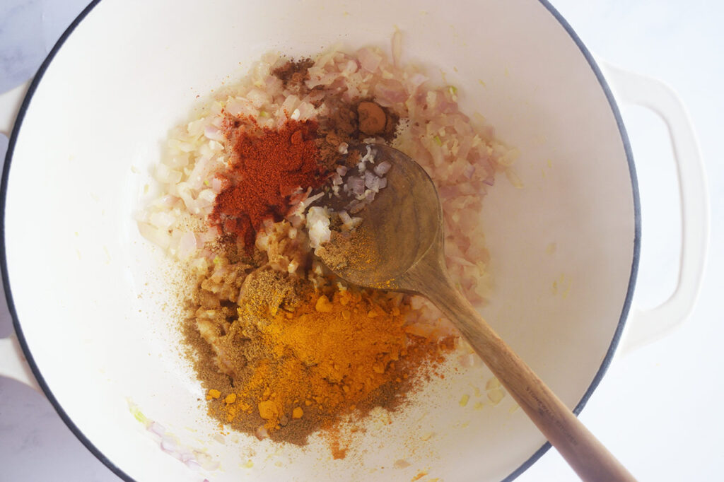 Dry spices added to sautéed onions, ginger, and garlic in a Dutch oven.