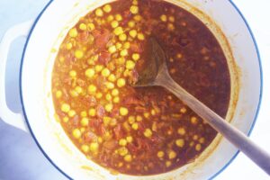 Broth and tomatoes added to a Dutch oven along with chickpeas.
