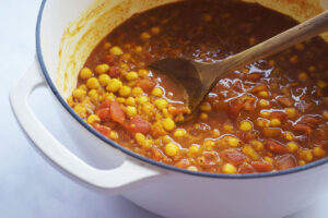Finished Moroccan Chickpea Stew in a Dutch oven with a wooden spoon resting in it.