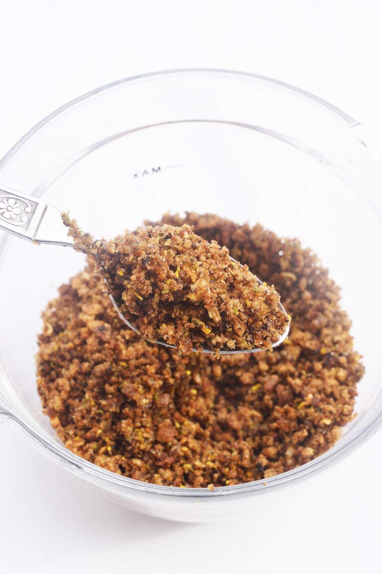 A spoon lifts up some Pangrattato from a glass bowl.