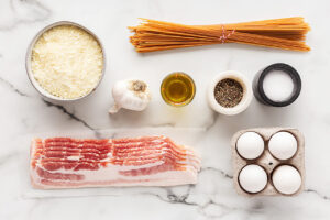 Pasta Carbonara Recipe ingredients on a white, marble surface.