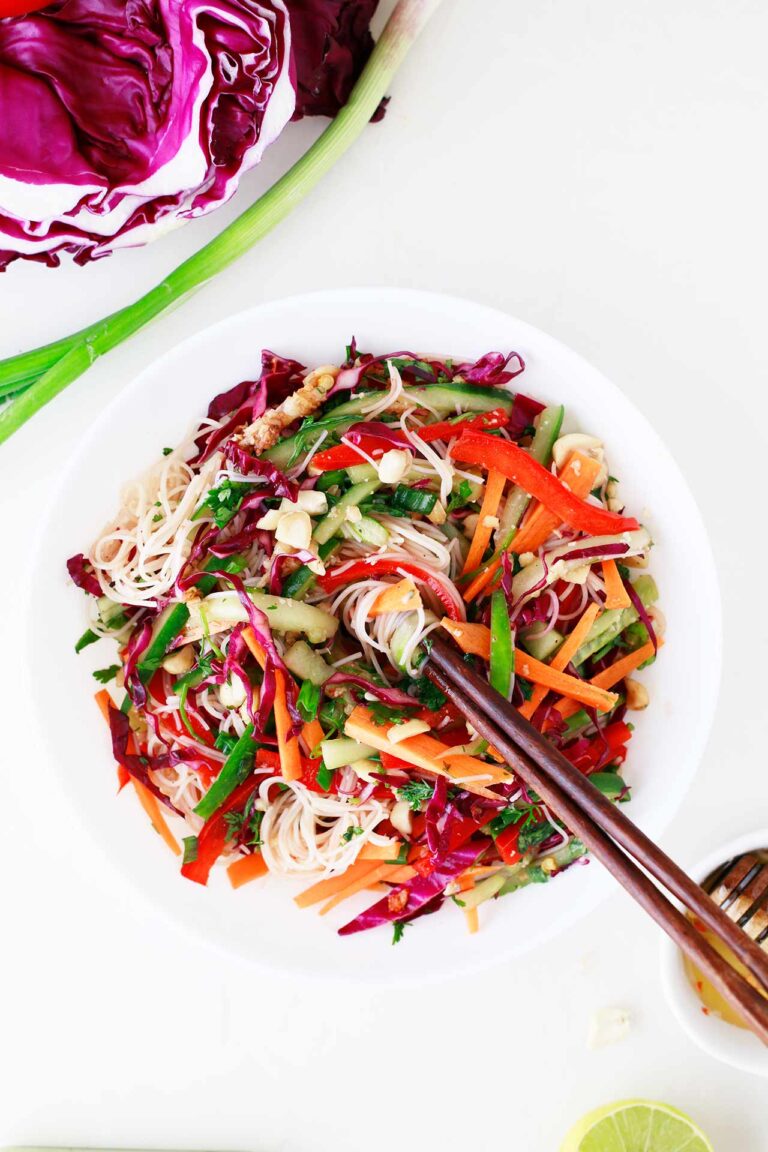 Overhead focus. White bowl filled with Spring Roll Salad. Chopsticks rest in the salad.
