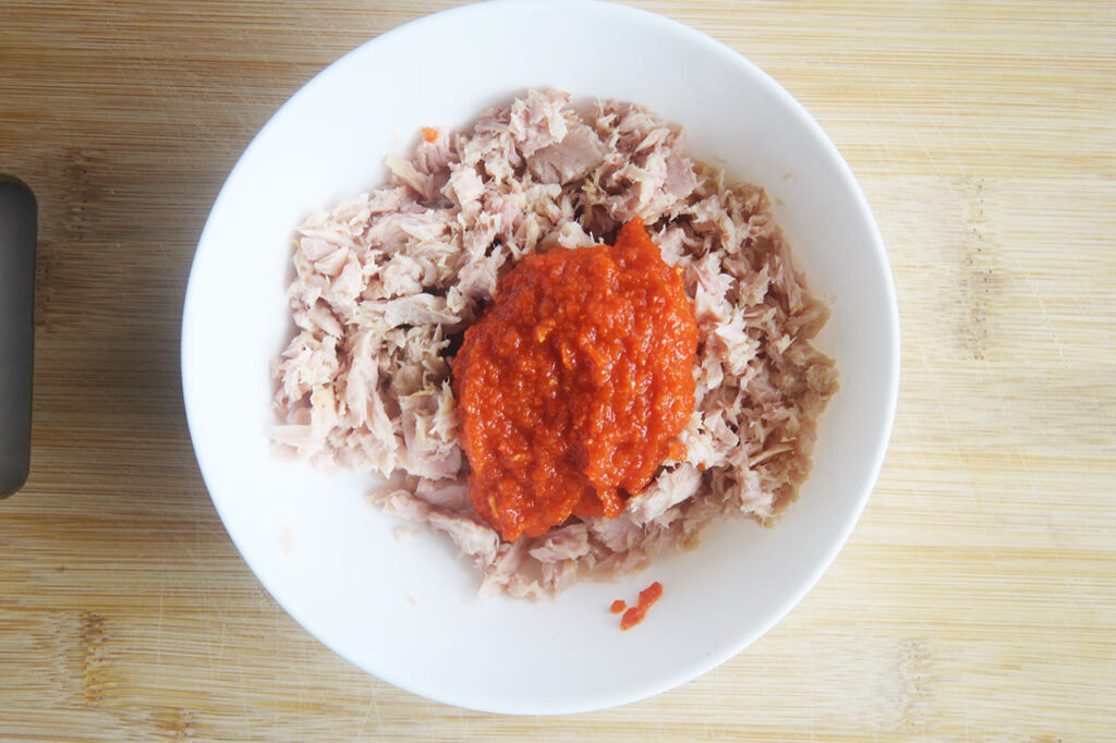Tuna and Sriracha sauce in a bowl to be mixed.