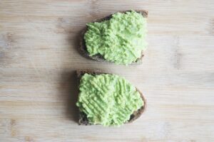 Mashed avocado spread over two slices of toast.