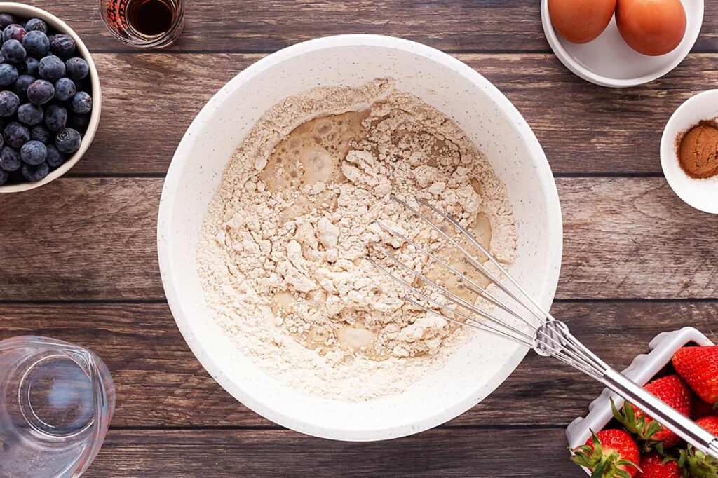 Milk added to flour in a mixing bowl.