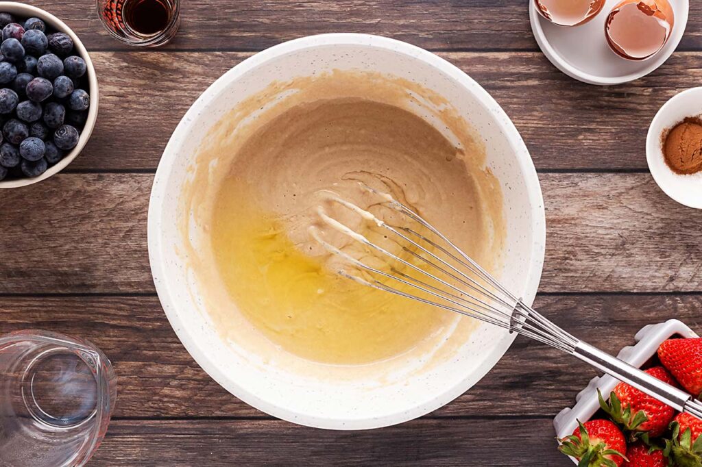 Eggs added to flour and milk in a mixing bowl.