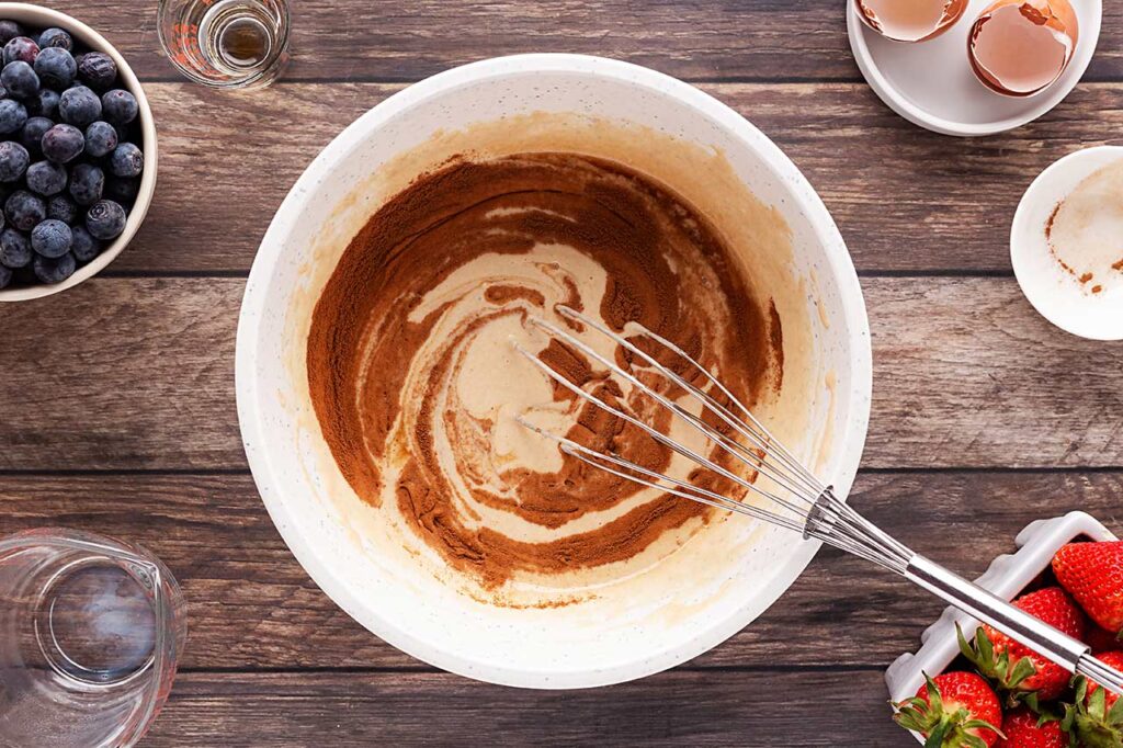 Mixing pancake batter in a large mixing bowl with a whisk.