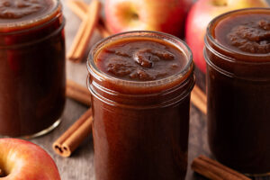Three open canning jars filled with apple butter.