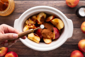 Adding salt to cut apples in a slow cooker crock.