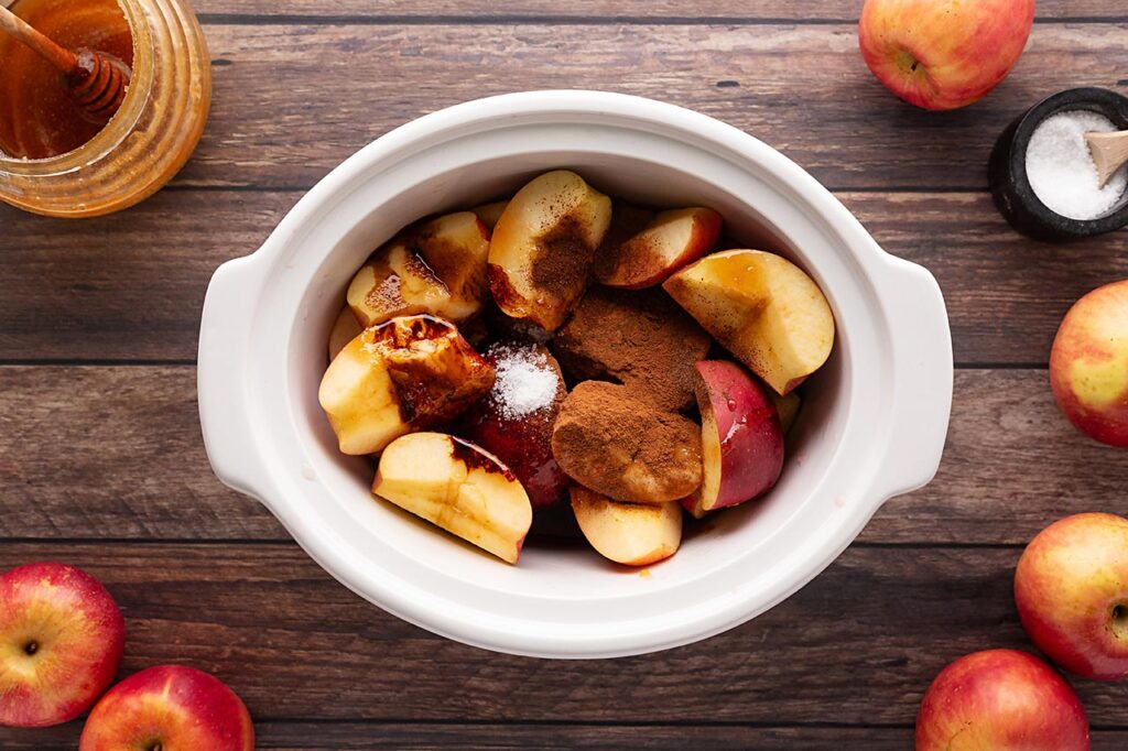 Salt added to cut apples in a white crock.