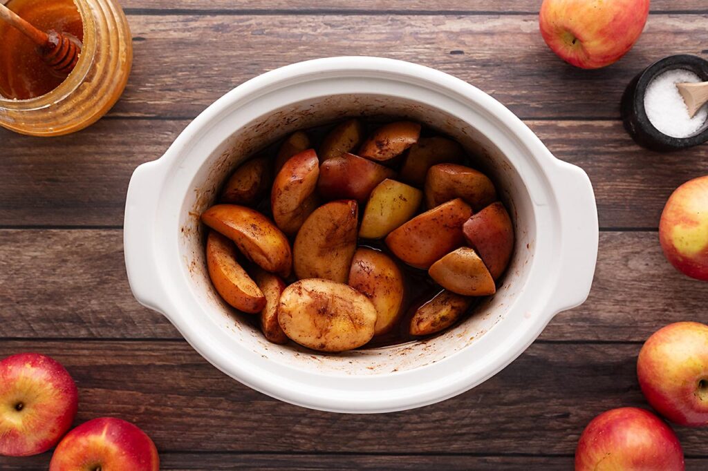 Mixed, cut apples in a slow cooker crock.
