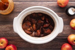 Cooked apples in a white slow cooke crock.