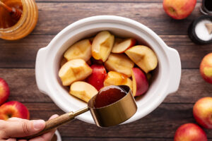 Adding honey to a crock of apples and apple juice.